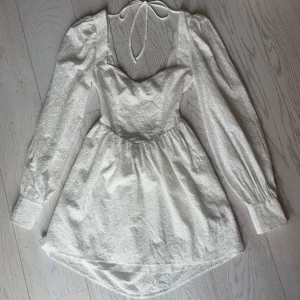 Sommarklänning  - En vit spetskläning av blommigt mönster och helt oanvänd. Klänningen är öppen i ryggen med snörning. En dröm att ha i garderoben nu på sommaren och nästa semester. 