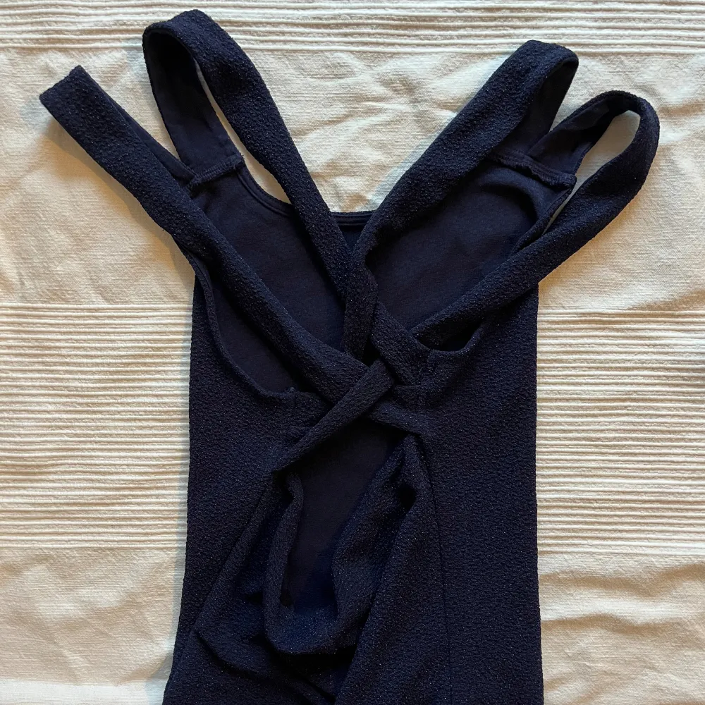 Mörkblå glittrig klänning med kors på ryggen, har endast använt 2 gånger Står tyvärr inte vilket märke det är då lappen är avklippt 😬. Mekot.
