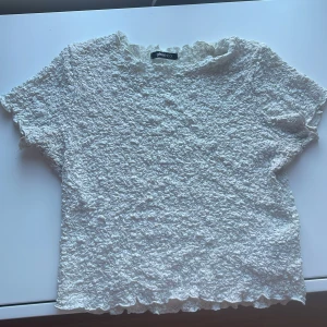 Croppad top - En vit croppad topp med ”skrynkligt” material från Gina tricot