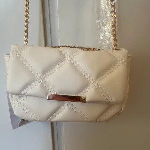 Liten handväska - Superfin handväska i beige och guld. Helt ny med prislapp kvar 