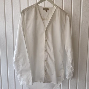Vit Whyred Skjorta - En tunn vit skjorta från Whyred. Storlek 48 (Medium). Annorlunda design, v-ringad utan krage. Perfekt till studenten / att ha under kavajen för dig som vill sticka ut.  Passar både dam och herr. Nypris var runt 1700kr.  Använd ca 2 ggr. Toppskick! ✨