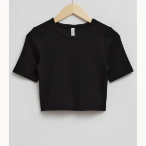 Kroppad t-shirt  - En svart kroppad T-shirt från hm, liknar den på bilden (lånad bild), väldigt liten i storlek 