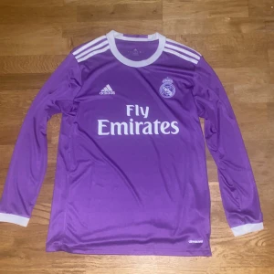 Real Madrid 2016-2017 Borta Tröja - Den ikoniska lila Real Madrid tröjan från 2016/17 säsongen. Real Madrid vann bland annat Champions League finalen mot Juventus i denna tröja. Tröjan är i bra skick, Storlek: M (Pris kan diskuteras)