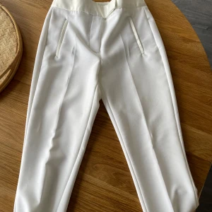 Vit Smokingbyxa Zara  - Vit smokingbyxa från Zara. Strl XS. Tight slacks passform.  Fläck bak på rumpan som nog går bort med men har ej testat själv. Endast använd 1 gång så i fint skick i övrigt. Inköpt för ett par år sedan. 