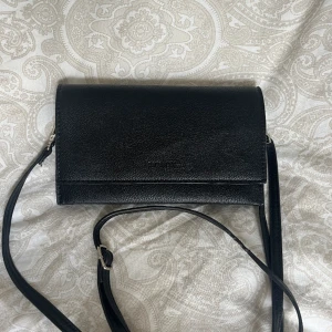 Axelremsväska  - En liten axelremsväska med justerbar axelrem som även går att ta bort för att använda den som kuvertväska. Är i mycket gott skick.