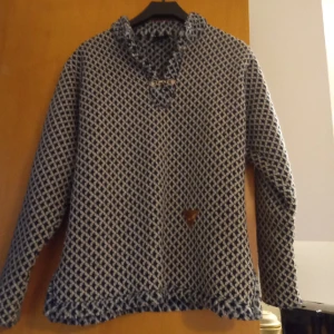 Tröja med hyske och hake knäppning .stl 134/140. - Fin och mjuk tröja med hyske och hake knäppning smårutig och stl 134/140.UP design  Sweden. Material Polyester 40 grader .Inget slitage finnes .