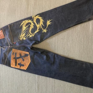 Evisu jeans - Säljer mina evisu jeans. De ser bra ut när man har på sig dom men har några små fel här och där, bak på byxorna där evisu loggan står har lädret lossnat. Två av de fyra knappar som sitter längst fram på byxorna har har också lossnat. Annars bra skick