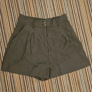 Högmidjade shorts  - Mititärgröna shorts med hög midja som är breda vid låren. 