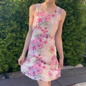  Sommar klänning -  Så söt blommig klänning som är perfekt nu till sommaren! Jättefina detaljer och små glansiga pärlor insydda runt blommorna! V-ringad rygg. Snören kan man knyta i ryggen eller längst fram beroende på vad man föredrar! 🌸💗