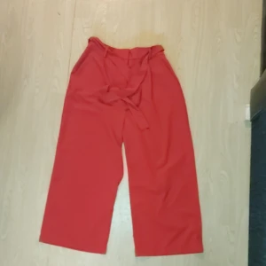 Tunna röda byxor - Byxorna är knall röda och med bälte i stl. 42 De är tunna och resår i midjan Använda! TRYCK EJ KÖP NU