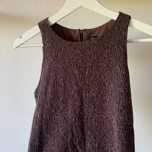 Brun klänning - Fin A-line klänning! Den har fickor!!!!! Brun med mönster på och knäpps med dragkedja längst med ryggen. Perfekta klänningen att strosa runt i!