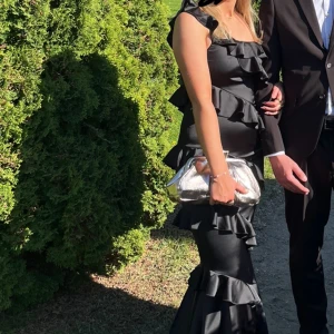 Balklänning - Svart balklänning med volanger från Boohoo. Använd 1 gång. Bra skick!  Storlek 38 men liten i storleken. Jag är 175 lång. Köpt för 900kr. 