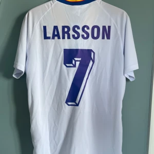 Henrik Larsson Sveriges Landslag som 1994 fotbollströja  - En otroligt snygg fotbollströja i bra skick med den svenska legendaren Henke Larsson på ryggen med tröjan från vm 1994 där Sverige kom på en tredje plats, kom gärna med frågor!