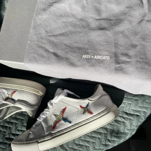 Axel Arigato clean 90 bird - Säljer ett par vita arigatos med fåglar på, köpt för ungefär 2500kr och säljer för endast 1099kr, säljer pågrund av att jag inte använder dem längre. Kommer med box, dustbag och papperspåsen. Kom gärna med bud och funderingar. Sänker vid snabb affär 