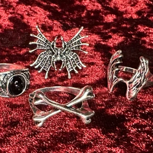 Fyra nya ringar Benknotor spindel Gothic Emo Metal Goth Rock Halloween  - Fyra nya snygga ringar med spindel, änglavingar, benknotor och svart konststen. Innerdiameter 1,9- 2,1 cm för att passa olika fingrar.  Nya och oanvända. En fin pressmeddelande till dig själv eller någon du tycker om. Vitmetall och konststen. Unisex.