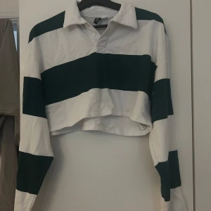 Croppad tröja - Superfin croppad tröja från H&M. Säljer då den är lite liten för mig. Den är vit och typ mörkgrön. Använt 1-2 gånger och är i bra skick. Storlek M.