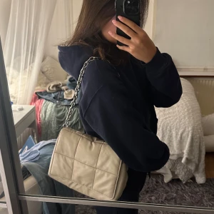 H&M Väska - Beige väska frän H&M. Två fack innuti + sidofack med dragkedja. Puffig medelstor väska med silverkedja i metall. Rymmlig.