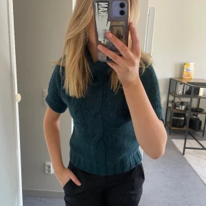 Stickad t-shirt - Stickad t-shirt i storlek 34 med polokrage. Tröjan är i bra skick och är mörk blå/grön