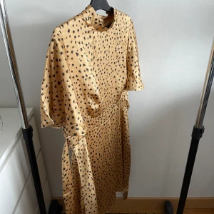 Glansig klänning  - Klänning med leopard-mönster. Finns skärp i midjan.  Använd fåtal gånger. 