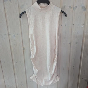 Ljusrosa ärmlös poloklänning - En ljusrosa ärmlös klänning med hög hals. Klänningen har en åtsittande passform och är tillverkad i ett mjukt och bekvämt material. Den har rynkade detaljer på sidorna som ger en smickrande silhuett.liten obehandlad fläck( sista bilden).Lappen med storlek och varumärke har klippts bort, men jag skulle säga att storleken är S/M.  Längd ca 83 cm Bredd ca 29 cm 
