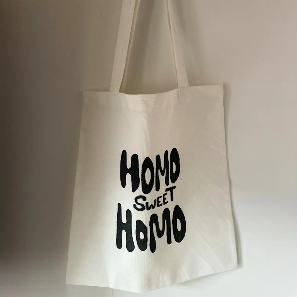 Handsydd tygkasse med motivet ”homo sweet homo”.   Tillverkad i 100% återvunna textilier. Motivet är handmålad med textilfärg.   Mått: 32x35 cm  Hämtas på Södermalm alternativt skickas med post. . Väskor.