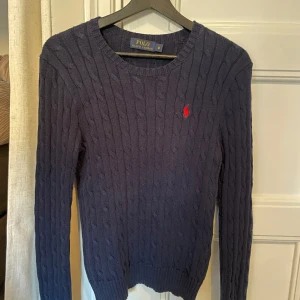 Ralph Lauren pullover - Klassisk kabelstickad långärmad pullover från Ralph Lauren i marinblått och storlek M. Sparsamt använd och inga defekter. Nypris ca 1700 kr.