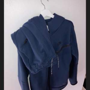 Fin Nike Tech Fleece dress i navy blå. Mycket bra skick! Koftan är M och byxor är L. Köptes för 2250kr och säljs för 1300kr. 