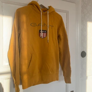Gant luvtröja - Senapsgul luvtröja från Gant i storlek S men sitter mer som M, har en liten fläck på ena ärmen men annars är den i bra skick. Fläcken går möjligtvis bort i tvätten.