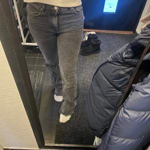 Ett par jeans ifrån Gina som är mid waist och är i färgen grå. De ett hål på vänstra benet.