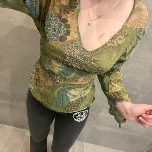 Finare blus med knytning - Cool blus med knytning! Kan knytas bakom ryggen som på bild 1 eller fram vid magen! Fint skick strl 42 men skulle säga att den passar mindre då knytningen går att justera.
