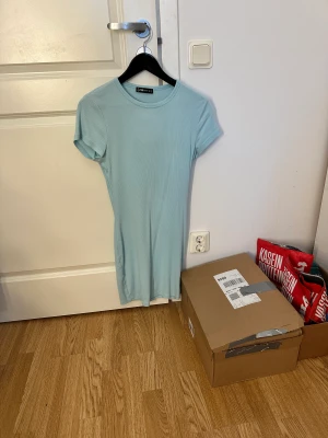 Klänning - Fin ljusblå ribbad klänning från New Yorker. Använd fåtal gånger så i fint skick.  Väldigt stretchig så passar många olika storlekar. Köparen står för frakten.