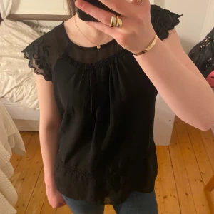 Fin svart blus från veromoda - Svart blus med korta ärmar med fina detaljer på, tröjan är i bra skick och köpt second hand! Storlek M men sitter som en Xs/S!