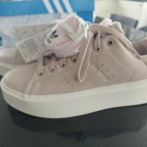 Adidas Original Stan Smith stl40  - Helt nya, ej använda Adidas Original Stan Smith stl 40 i Orginalkartong.  Köpta för 1299kr.  Gammelrosa typ. En liten miniväska hänger med i köpet, sitter fast på skosnöret. Men den går att ta bort.