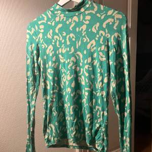 Fin grön långärmad tröja i leopard liknande mönster, tröjan har en liten krage som man ser på bild 1 och 2, köpte i samband med ett klädtema i grönt, aldrig använt efter det💕
