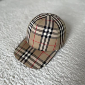 ÄKTA burberry keps -  Säljer nu denna snygga, äkta Burberry-keps som är i perfekt skick (10/10). Pris: 2000 kr (nypris 3500 kr). Anledningen till försäljningen är att den är lite för liten för mig. Tyvärr har jag inte kvar boxen eller kvittot. Men den är 100% ÄKTA🔥🔥