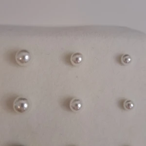 Silverfärgade pärlörhängen - Ett set med silverfärgade pärlörhängen i olika storlekar. Örhängena är runda och har en klassisk design som passar för olika tillfällen.