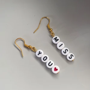 Örhängen med bokstäver - Unika roliga örhängen med bokstavspärlor. Text ”Miss You” följt av ett hjärta. Köpta på marknad. Passar perfekt om man har fler hål i öronen och kan matcha med andra örhängen.
