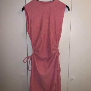 Rosa klänning  - längd: 90 cm Axelbred: 35 cm Väldigt bra skick, stretchigt tyg!  Band på höfterna som går att spänna!