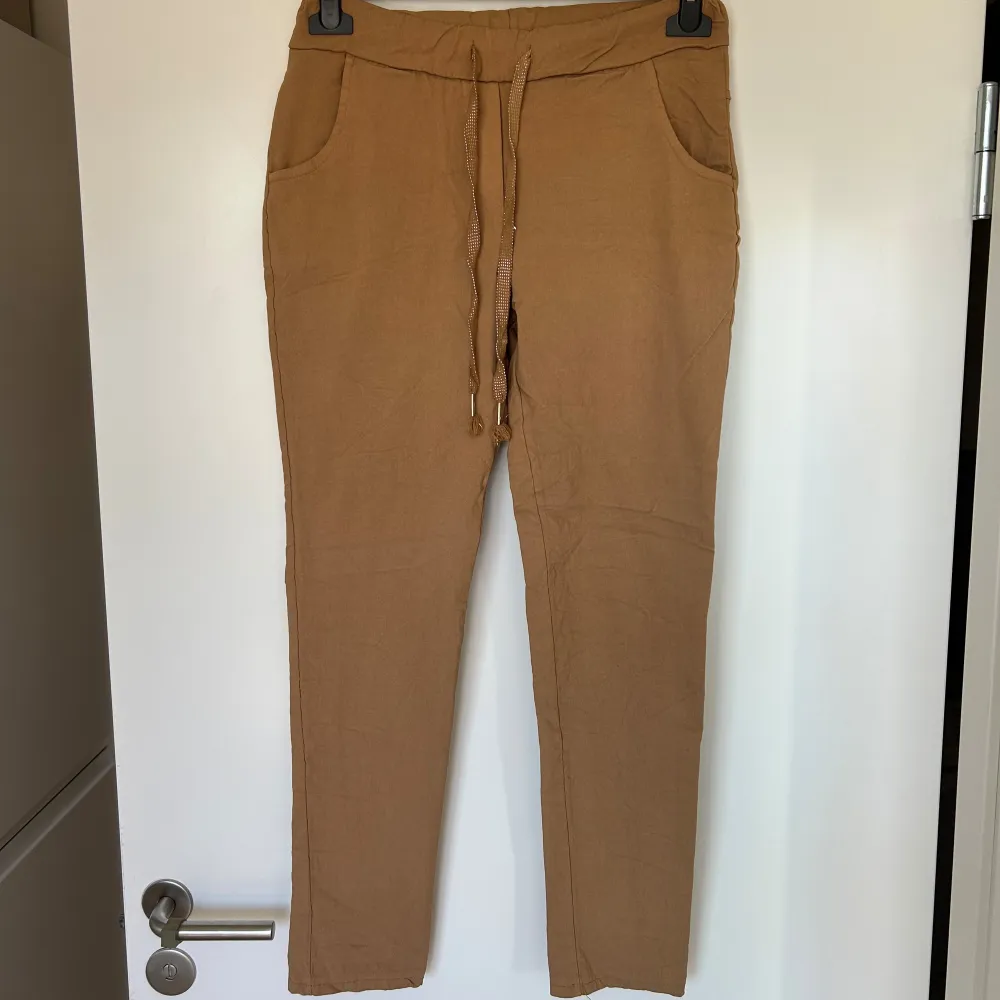 Beiga stretchiga chinos med resår och knytning i midjan. Köpta på By Carima och stl motsvarar ungefär 36 (onesize). Färg och material framgår av bild 3. Nyskick, endast testade! . Jeans & Byxor.