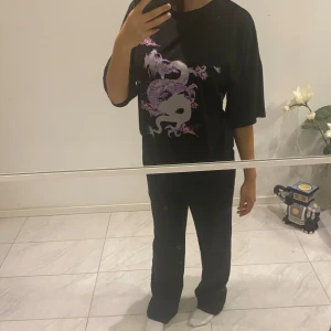 Svart tröja  - En svart tröja med lila design. Storlek S.