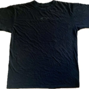 Oakley Tisha - Svart Oakley Tisha från 00talet Sitter oversized Väldigt snygg, coolt tryck 8/10 condition Messa för mer bilder Pris kan diskuteras  