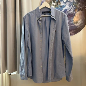 Blå skjorta från Ralph Lauren - Säljer en snygg blå skjorta från Ralph Lauren i storlek L. Skjortan är slim fit och har långa ärmar. Den är tillverkad i bomull och har knappar framtill. Perfekt för både vardag och fest!
