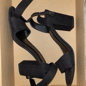 Svarta sandaler från Din Sko - Säljer ett par snygga svarta sandaler från Din Sko i storlek 37. De har en bred klack och är gjorda i mocka. Perfekta för både vardag och fest! De har en justerbar rem runt ankeln för bästa passform. Pris kan diskuteras!