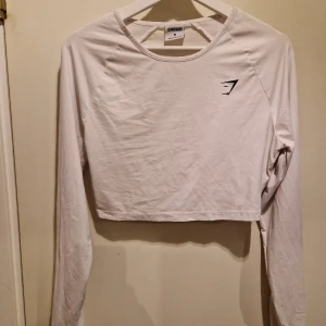 Tröningströja M - Croppad vit tröningströja från gymshark i storlek M. Med hål för tummen på ärmen 