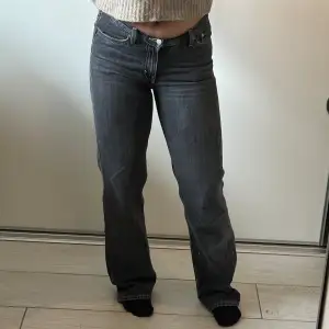 Mörkgråa lågmidjade raka jeans från Weekday med ljusa sömmar. Storlek 27. Slitna längst ner på benen på baksidan men det är inget man tänker på när man väl har på dem. 