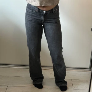 Lågmidjade jeans - Mörkgråa lågmidjade raka jeans från Weekday med ljusa sömmar. Storlek 27. Slitna längst ner på benen på baksidan men det är inget man tänker på när man väl har på dem. 