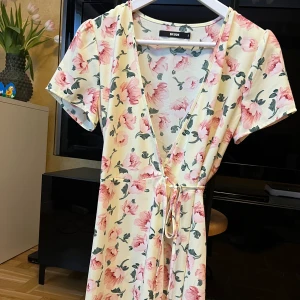 Omlott blommig klänning  - Blommig fin kortärmad omlottklänning från Bikbok. Se bilder för att se den på. Storlek S. Sparsamt använd. 