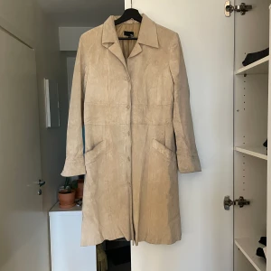 Vårkappa i mocka - Superfin vårkappa i äkta mocka och vintage stuk som inte har blivit använd på länge. I väldigt fint skick, men den har fläckar på ryggen efter regn som jag tyvärr inte haft möjlighet att ta bort. Storlek 42, men sitter perfekt på storlek 36-38!