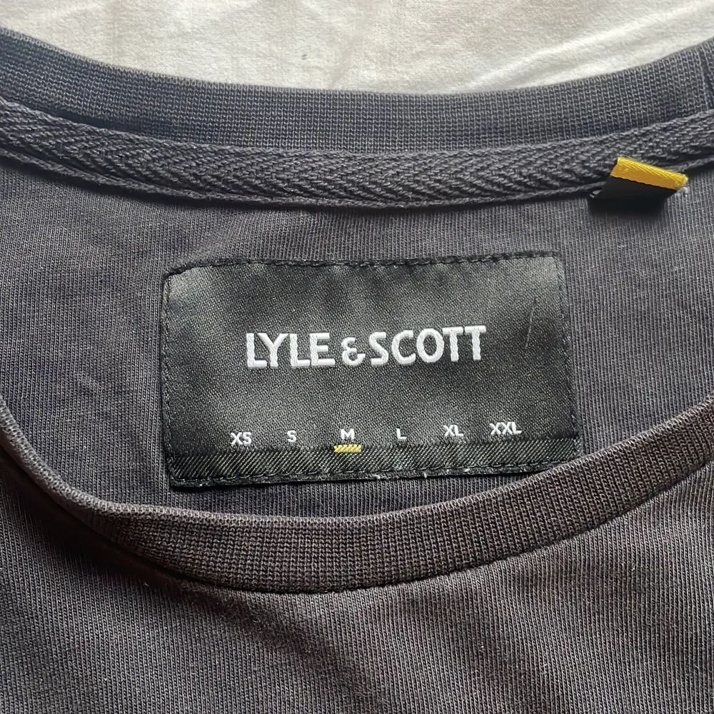 En svart Lyle&Scoot T-shirt med rosa, vita och ljusblå ränder på ärmarna. Tröjan är i storlek M. Inga defekter eller fläckar🥰 Hör av er för fler bilder/ frågor!💕. T-shirts.