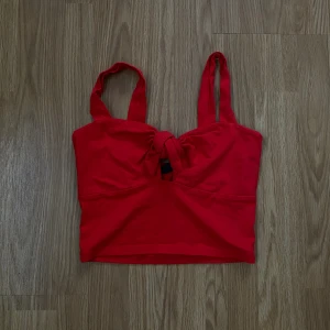 Linne med rosett  - Linne med rosett från Gina Tricot, slutar vid naveln. Helt ny har endast tagit bort prislappen och testat den. Mer julröd i färgen. 